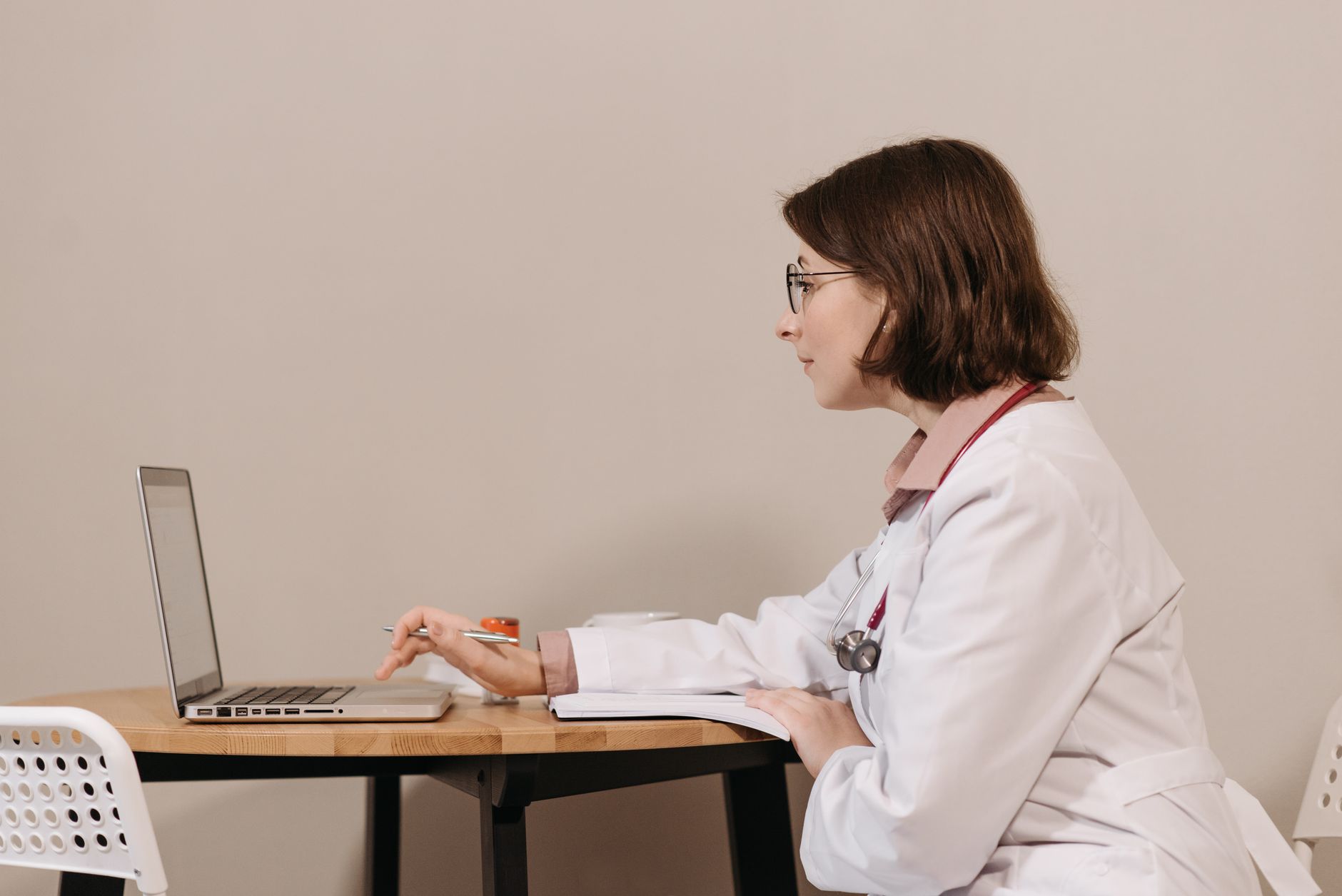 Profissional de saúde diante do computador no consultório, consultando o registro de um paciente